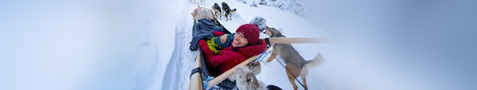 Kobieta z dzieckiem na saniach ciągniętych przez psy
